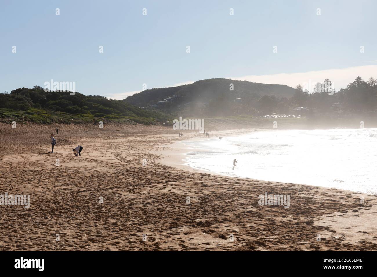 Am frühen Morgen geht die Sonne am Avalon Beach in Sydney unter, während Surfer zu den Wellen des Ozeans, NSW, Australien, fahren Stockfoto