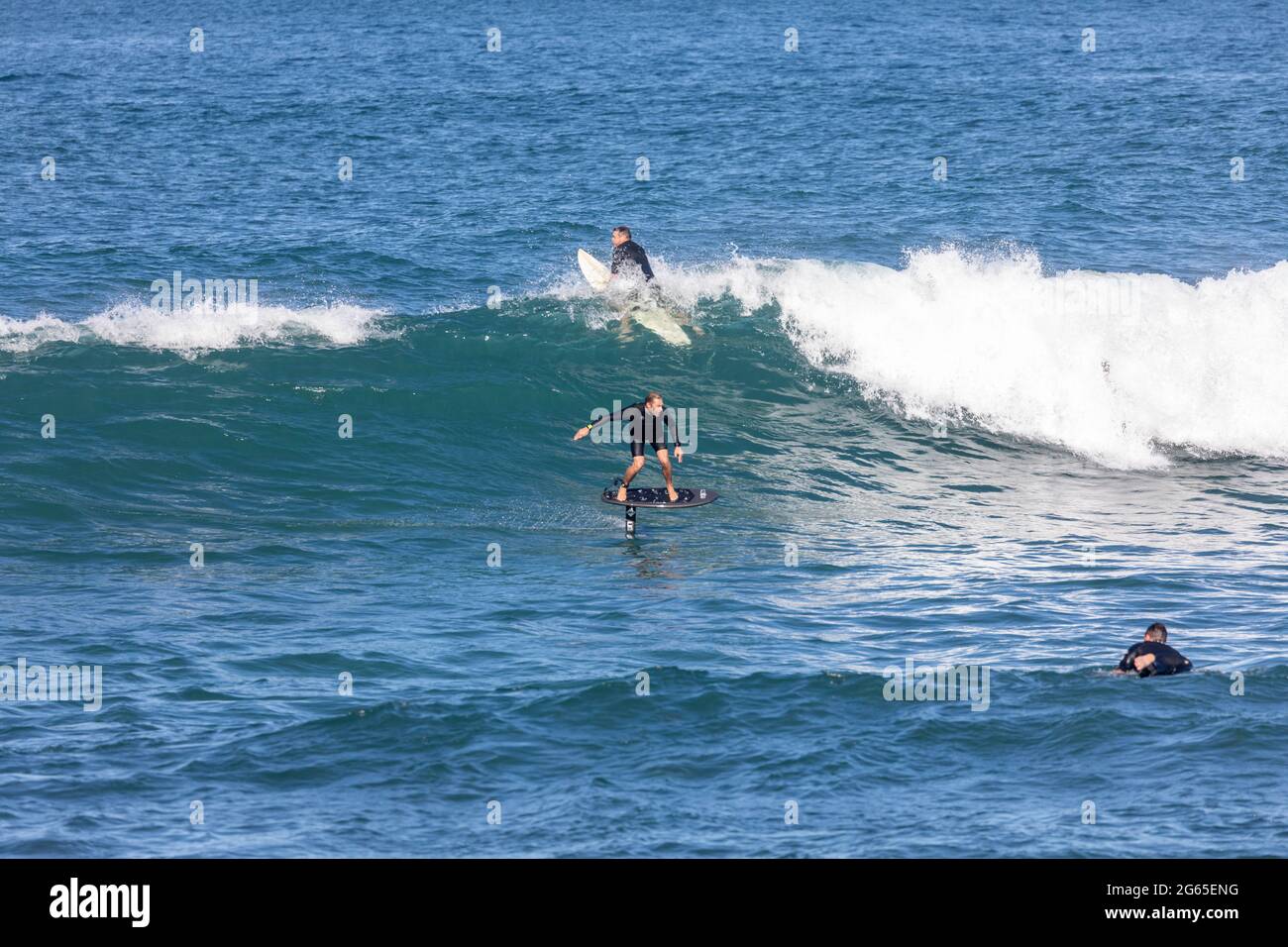 Surfen im Meer auf einem Tragflächenboot und traditionelle Surfbretter am Avalon Beach in Sydney, NSW, Australien Stockfoto