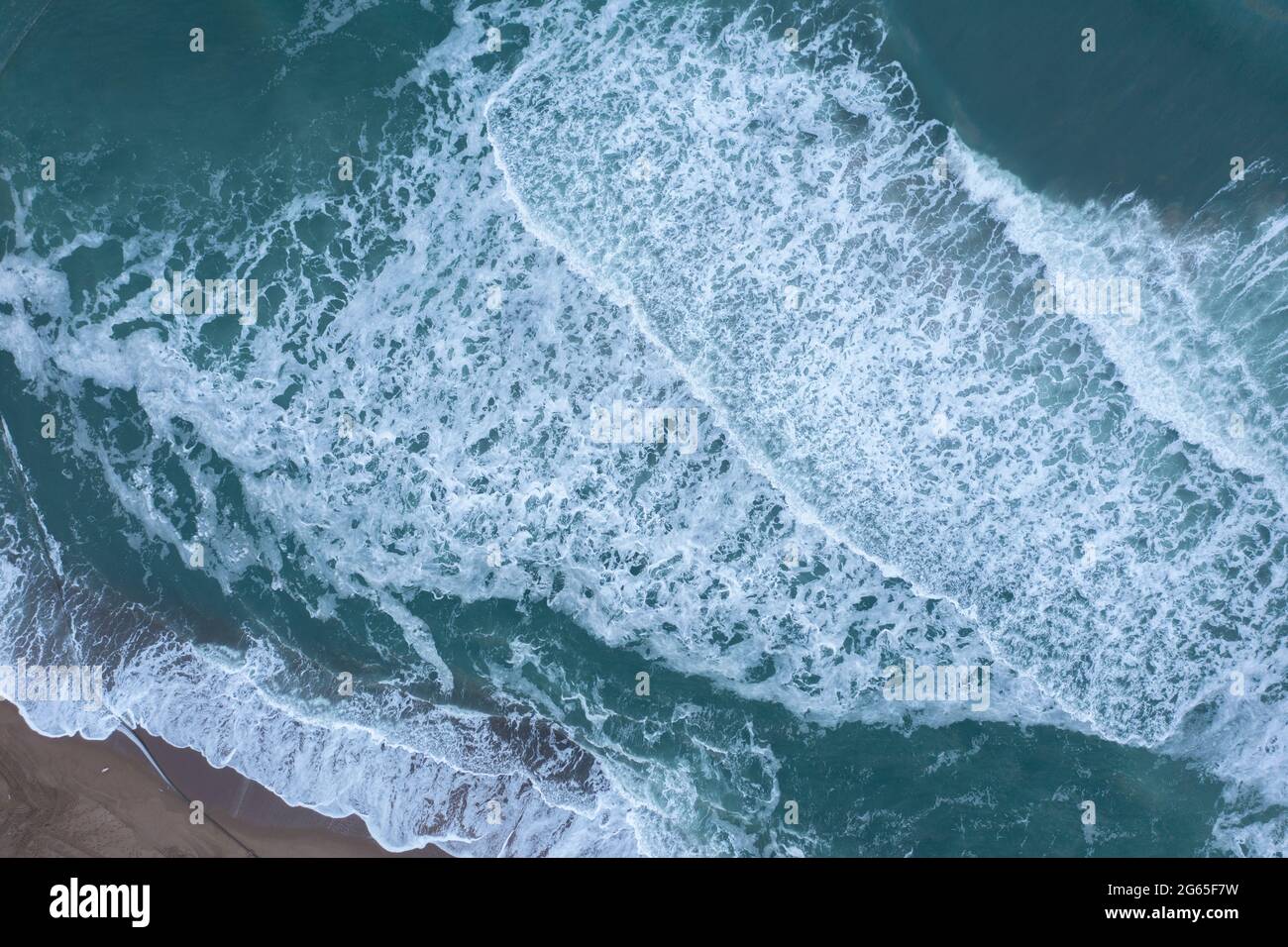Die Meereswelle läuft auf einem flachen Küstenstreifen. Stockfoto