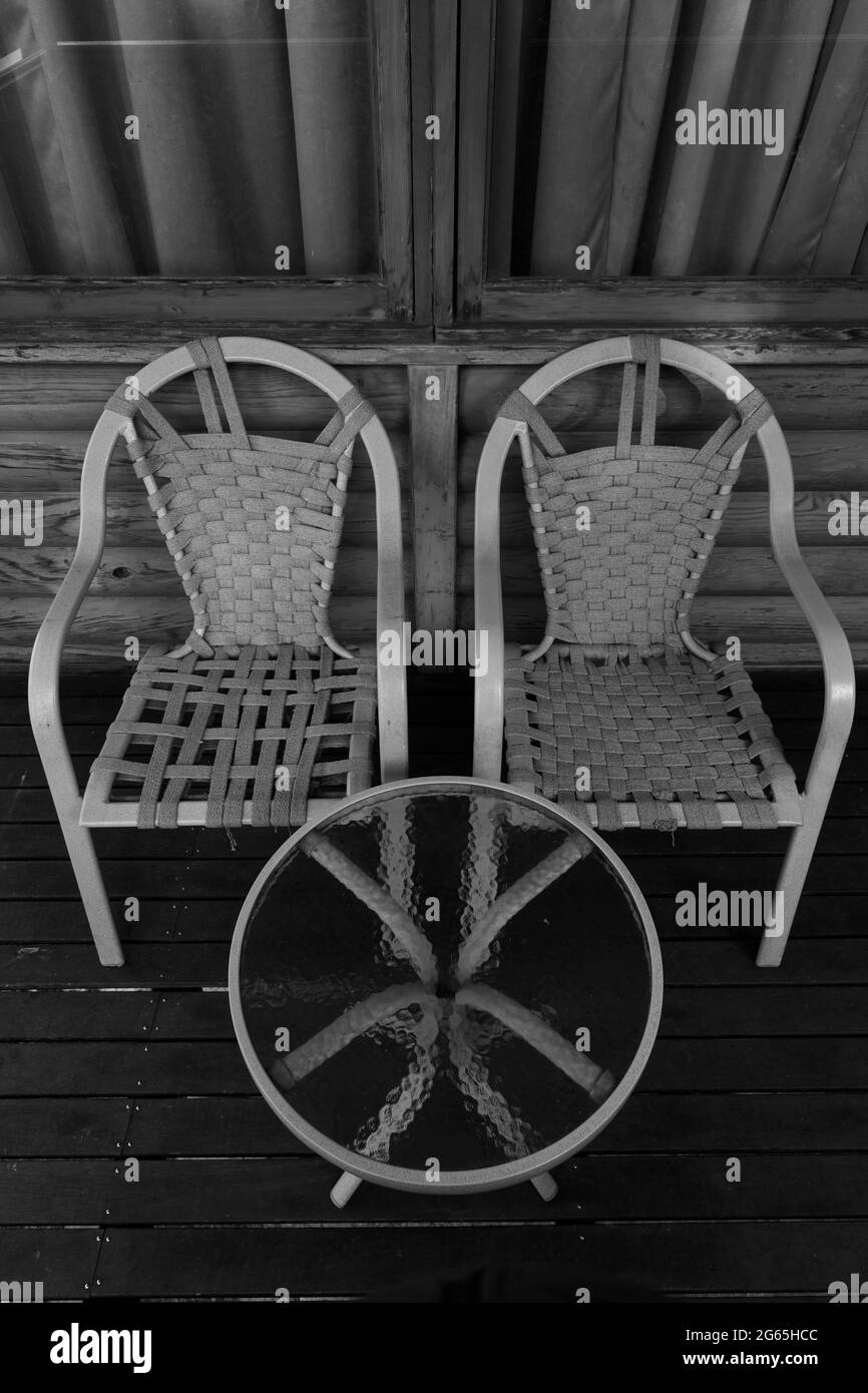 Ein Paar Stühle und ein runder Tisch mit Glas nebeneinander Stockfoto