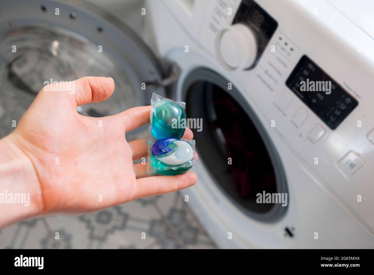 Personen legen spezielle Reinigungskapseln oder -Kapseln mit schmutziger  Kleidung in die Waschmaschine Stockfotografie - Alamy