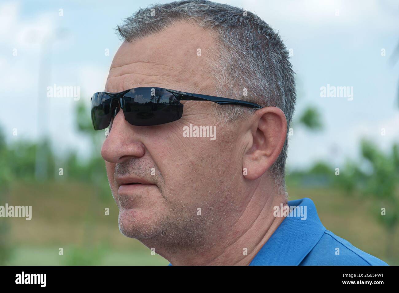 Männergesicht in dunkler Sonnenbrille, Nahaufnahme, verschwommener Hintergrund mit Bokeh-Elementen. Stock-Fotografie. Stockfoto