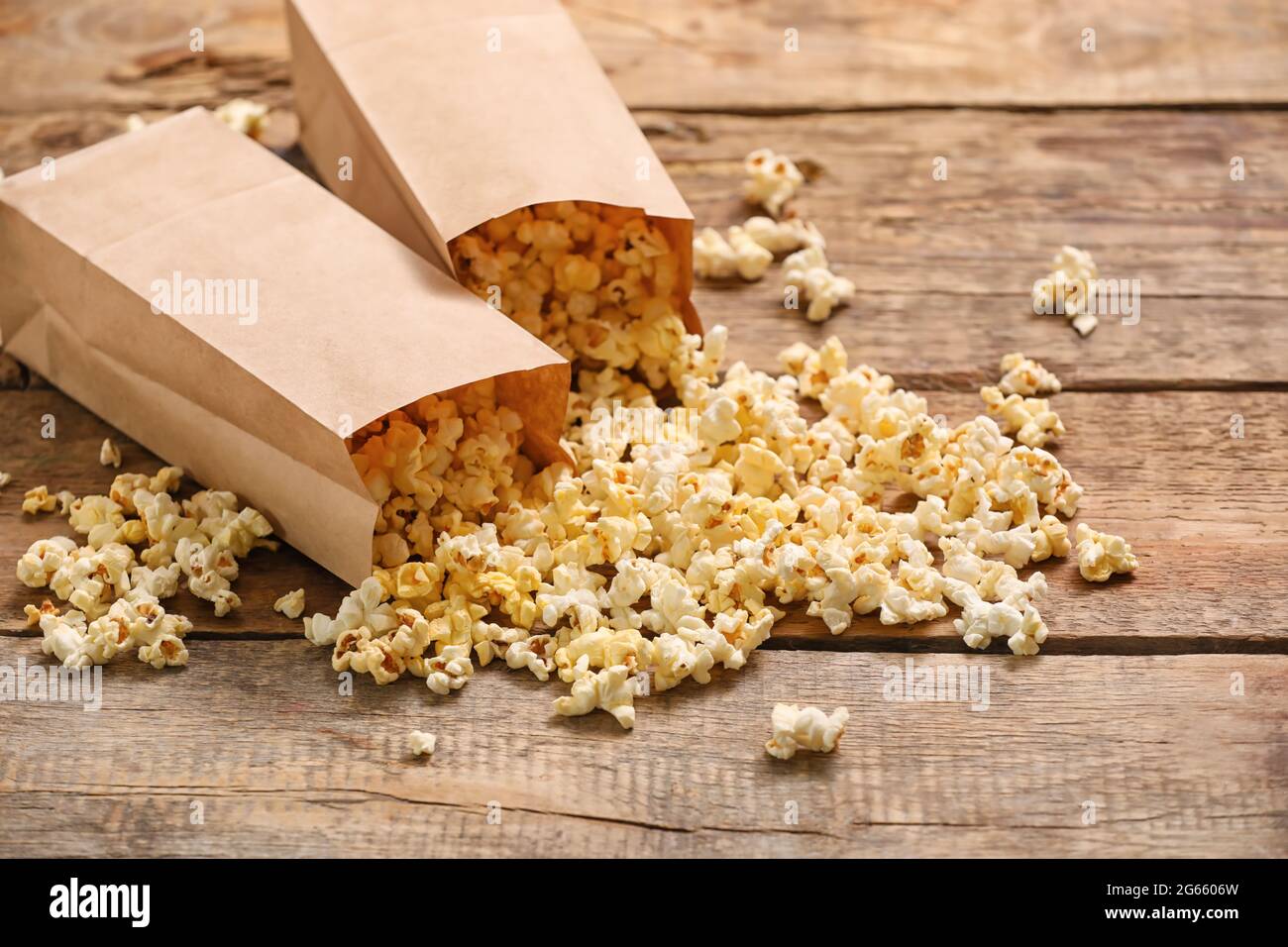 Papiertüten mit leckerem Popcorn auf Holzhintergrund Stockfoto