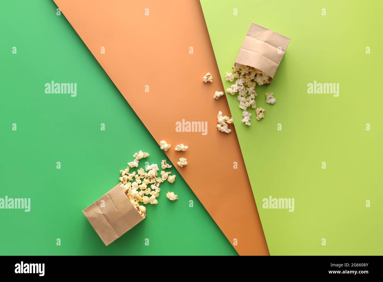 Papiertüten mit leckerem Popcorn auf farbigem Hintergrund Stockfoto