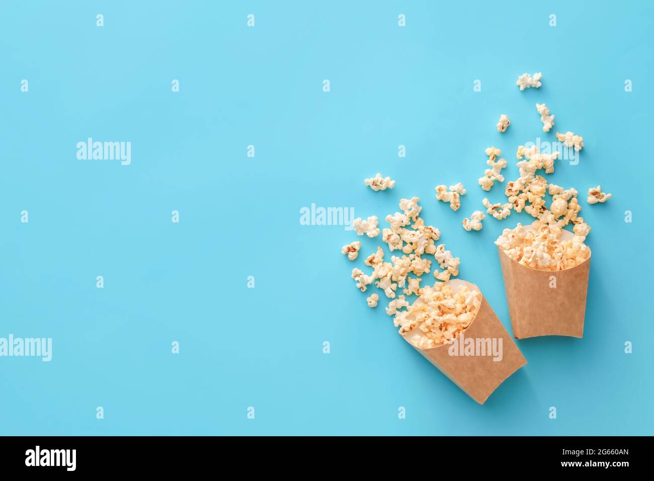 Papiertüten mit leckerem Popcorn auf farbigem Hintergrund Stockfoto