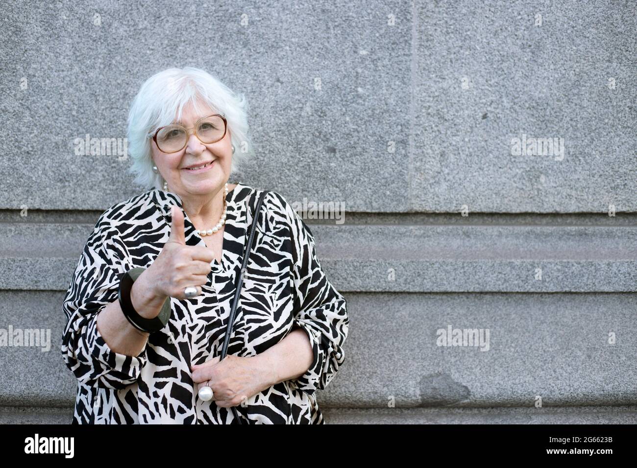 Ältere Frau, die mit Daumen im Freien in die Kamera schaut Stockfoto