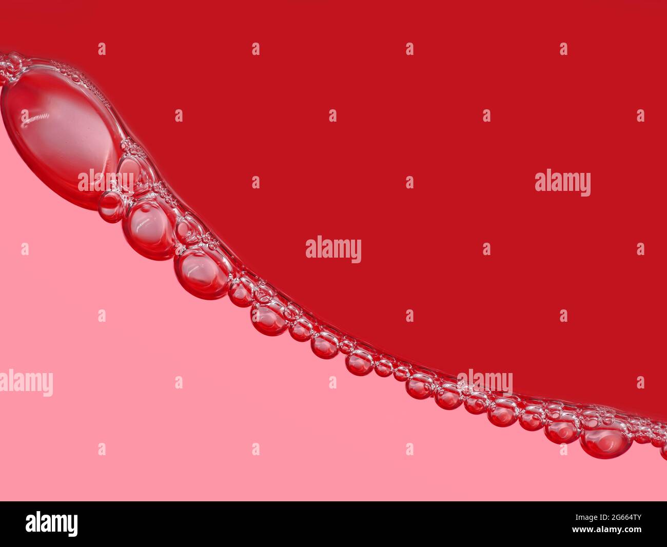 Luftblasenkette auf der Oberfläche in rotem Softdrink, Nahaufnahme, abstrakter roter Hintergrund von Blasen Stockfoto
