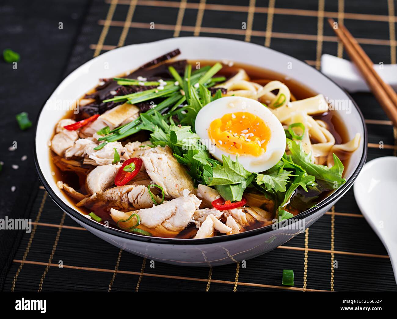 Miso-Suppe. Japanische Ramen-Suppe mit Huhn, Ei, Nori und Nipposinica auf dunklem Grund. Stockfoto