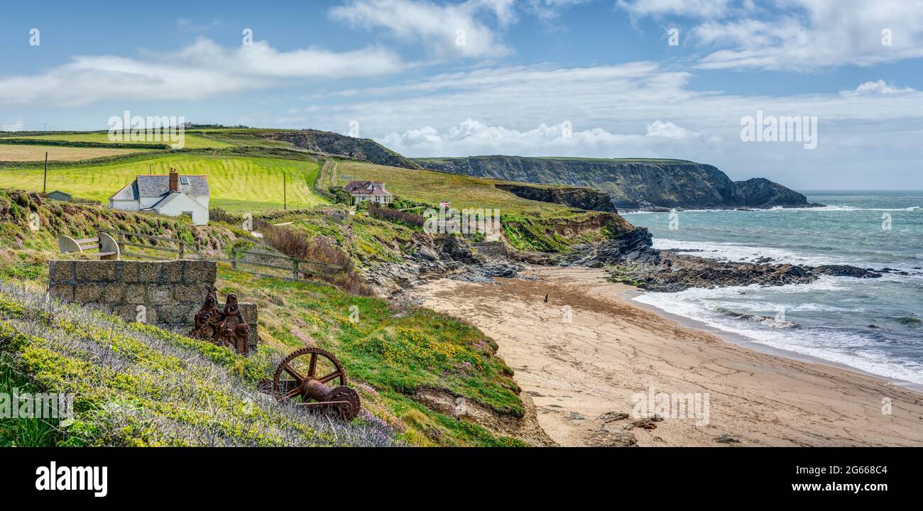 Eine Panoramalandschaft von Gunwalloe auf der Lizard, Cornwall. Alte Bootswinden, Häuser auf dem Küstenweg, ein schöner Strand und ländliche Klippen. Stockfoto