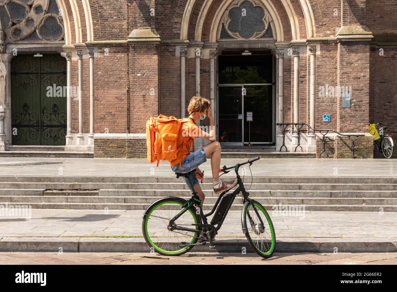 Eindhoven, Niederlande 18. Juni 2021. Guy auf einem Fahrrad, der für die niederländische Firma Thuisbezorgd arbeitet, wartet auf seine neue Bestellung, während er unterwegs ist Stockfoto