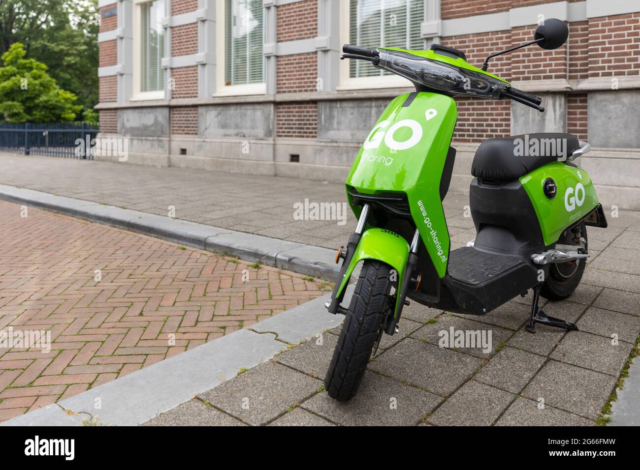 Breda, Niederlande 28. Juni 2021. Grüner Elektroroller, der auf einem Bürgersteig in der Stadt geparkt ist und über eine App gemietet und verwendet werden kann. Nachhaltiger Umweltschutz Stockfoto