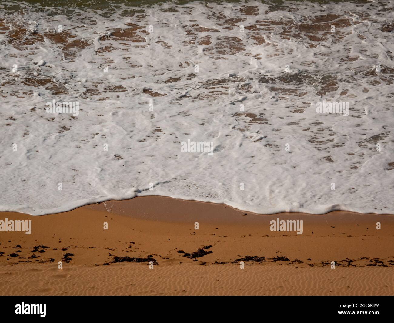 Weißer Schaumstoff, bekannt als Meer-, Ozean- oder Strandschaum, der durch die Erregung des Meerwassers entsteht Stockfoto