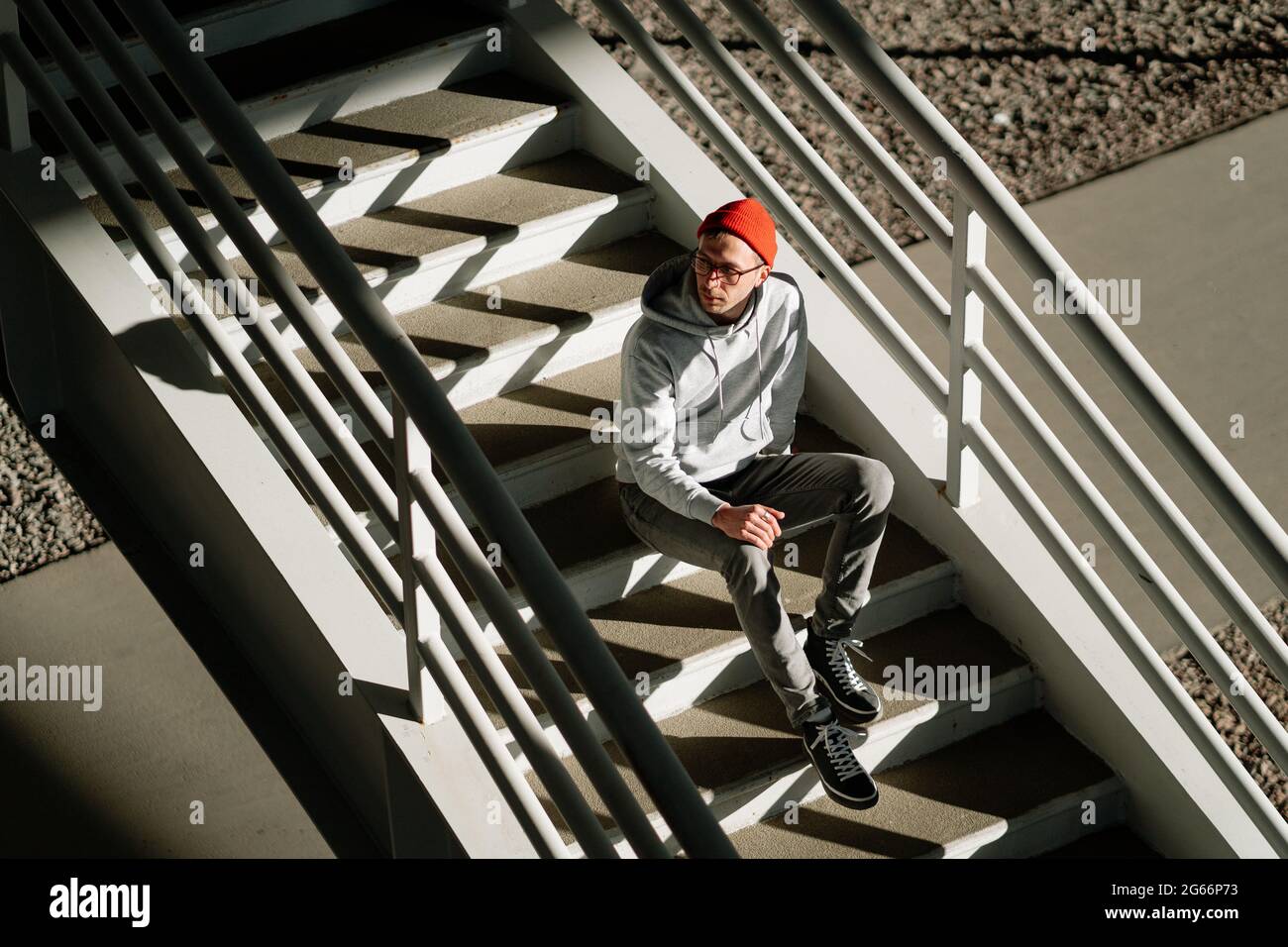 Männer Hipster allein auf Treppen in städtischen Gebäuden tragen trendige Brillen und Street-Fashion-Kleidung Stockfoto