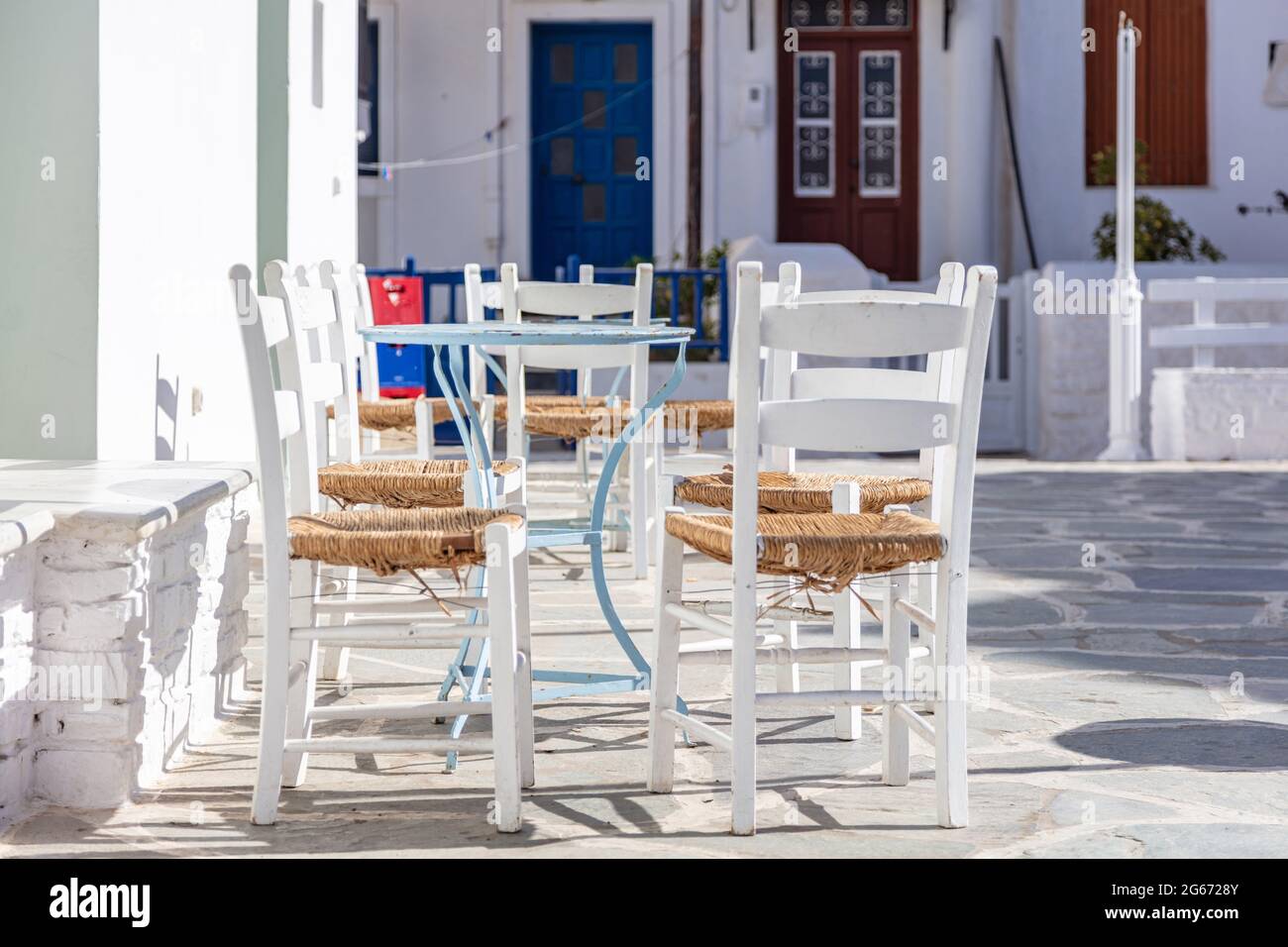 Griechische Insel, Café-Bar im Freien. Typische Cafeteria mit Tisch und Stühlen. Leere Plätze, sonniger Tag in Kythnos Chora Dorf gepflasterte Gasse. Sommer VA Stockfoto