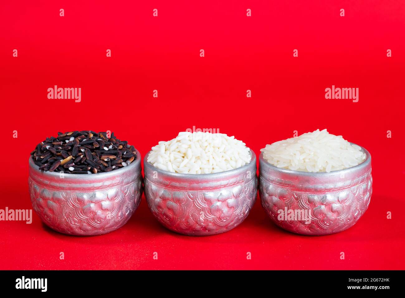 Drei Arten von thailändischem Reis in einem silbernen Behälter. Auf rotem Hintergrund und Kopierbereich. Stockfoto