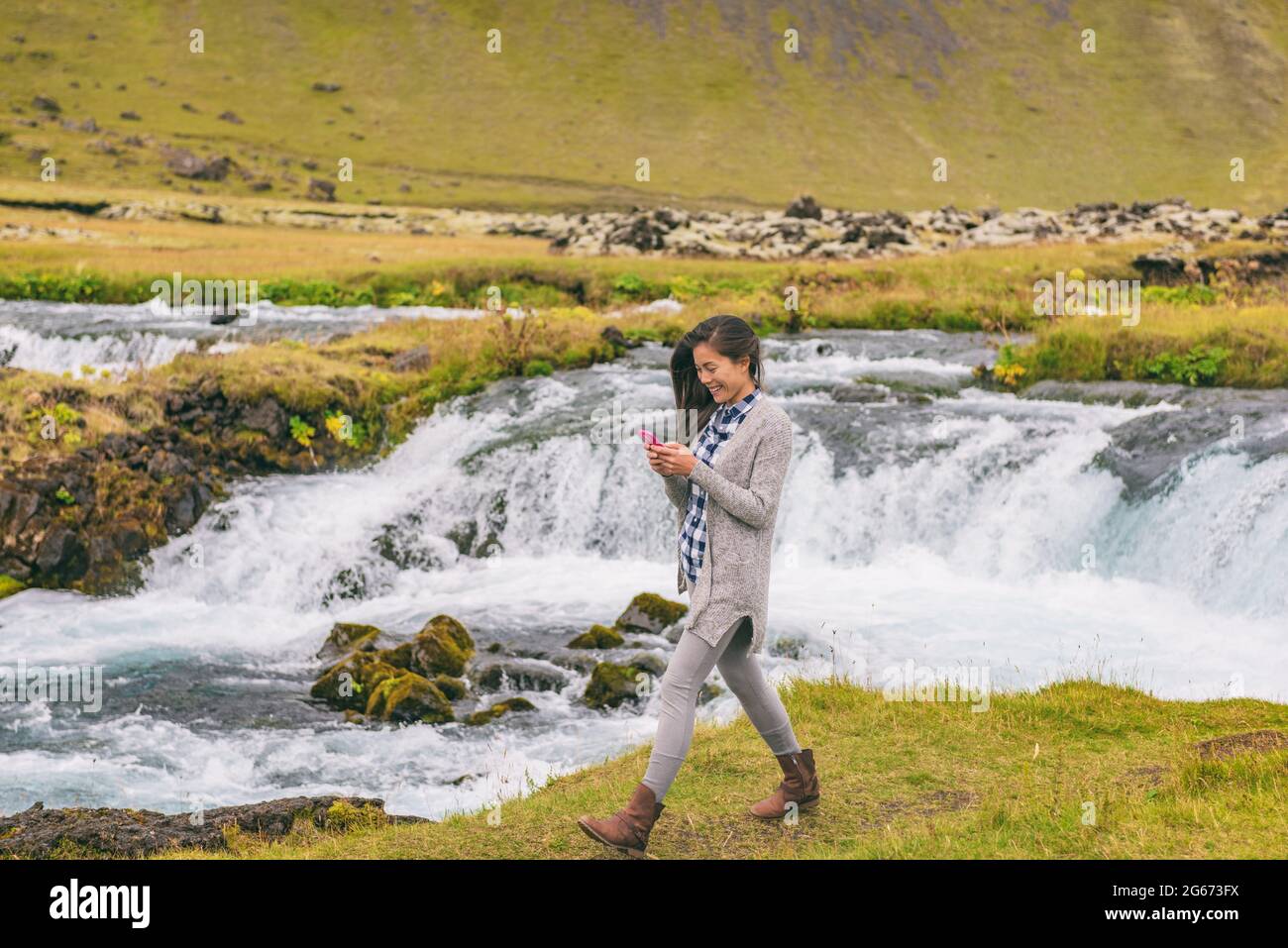 Frau, die am Wasserfall auf Island vorbeiläuft. Mädchen Tourist in legerer Kleidung Besuch isländische Naturlandschaft Stockfoto