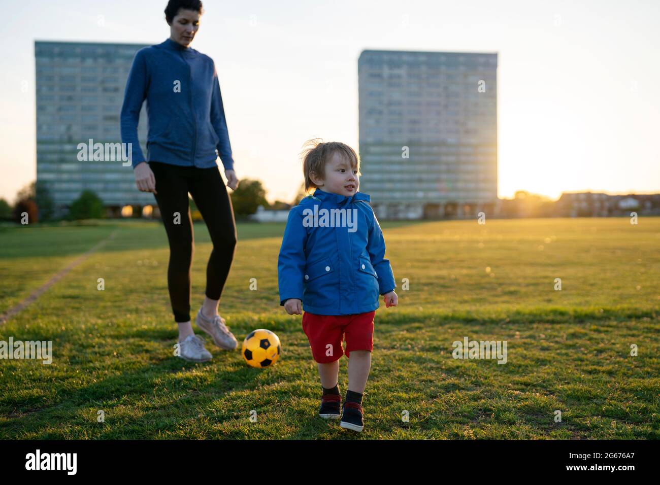 Ein kleiner Junge, der mit seiner Mutter in London Fußball spielt Stockfoto