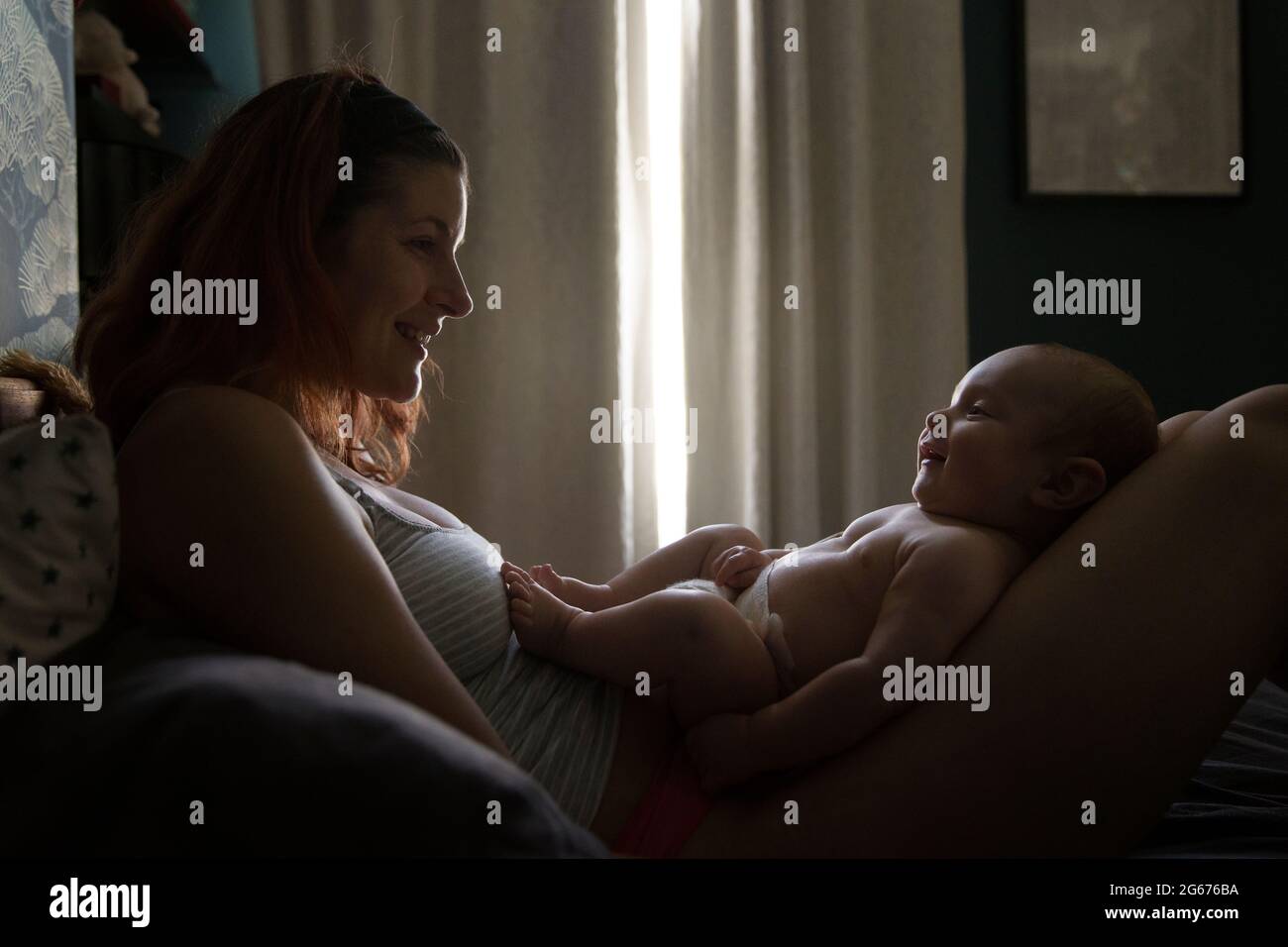 Eine Mutter, die mit ihrem Baby auf einem Bett liegt Stockfoto