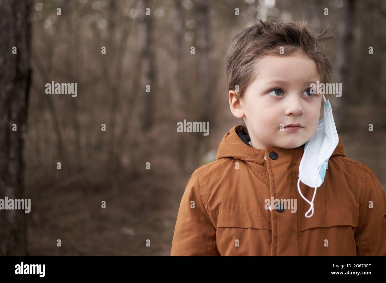 Porträt eines Jungen, der seine Schutzmaske nach der Quarantäne im Wald auszieht Stockfoto