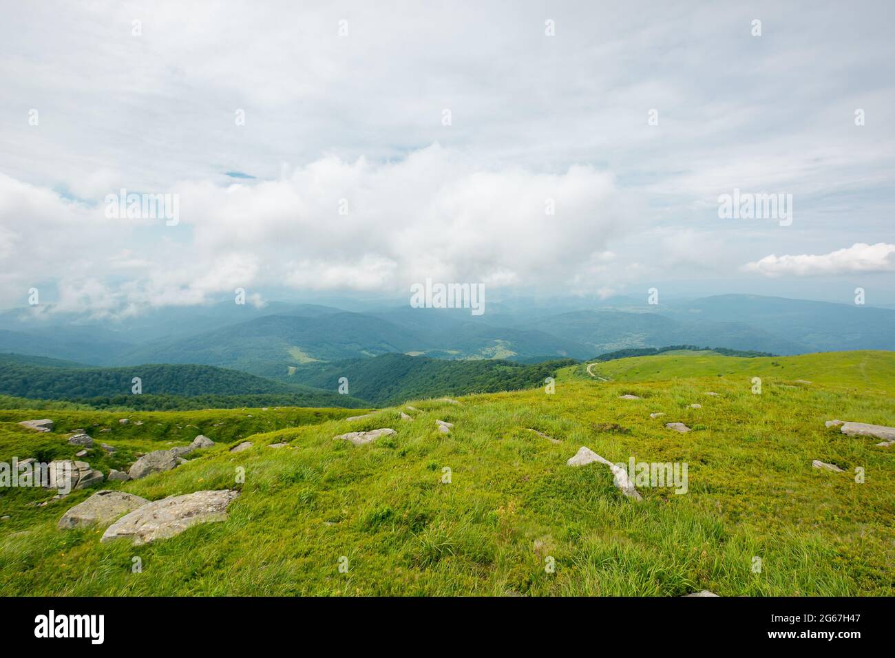 Sommer Berglandschaft. Schöne Naturlandschaft. Steine auf den grasbewachsenen Hügeln Rollen in den fernen Kamm unter einem bewölkten Himmel. Reise zurück Coun Stockfoto