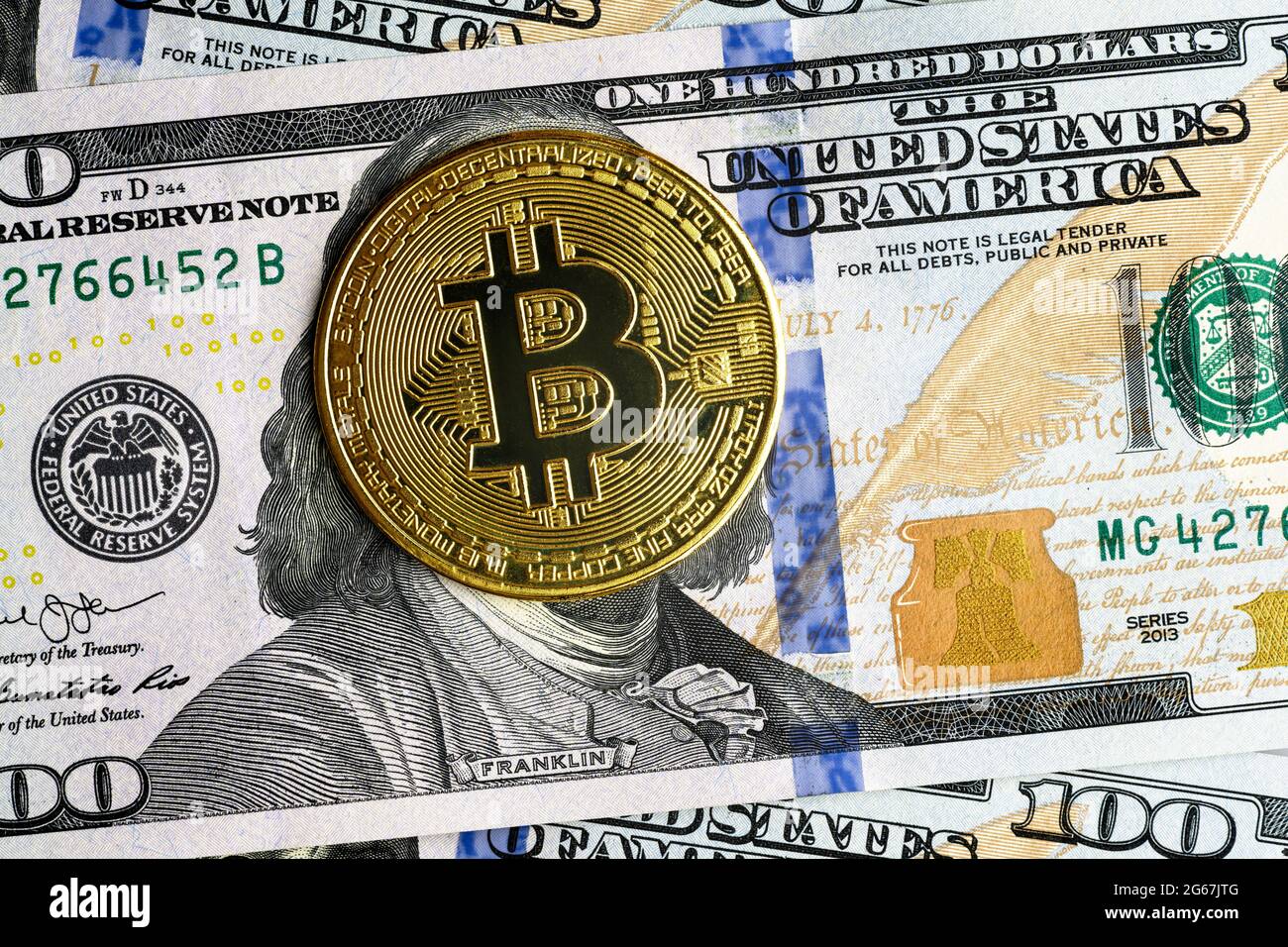 Bitcoin vs. US-Dollar, Goldbitmünzen auf 100-Dollar-Schein. Digitale Krypto-Währung Bitcoin verbirgt Franklin Gesicht auf Geldschein. Konzept der Bitcoin-Zahlung Stockfoto