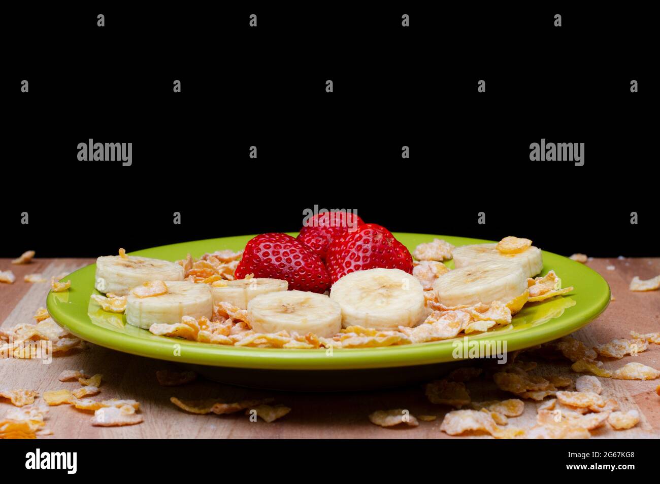 Erdbeere, Banane und Getreide auf einer grünen Schale Stockfoto