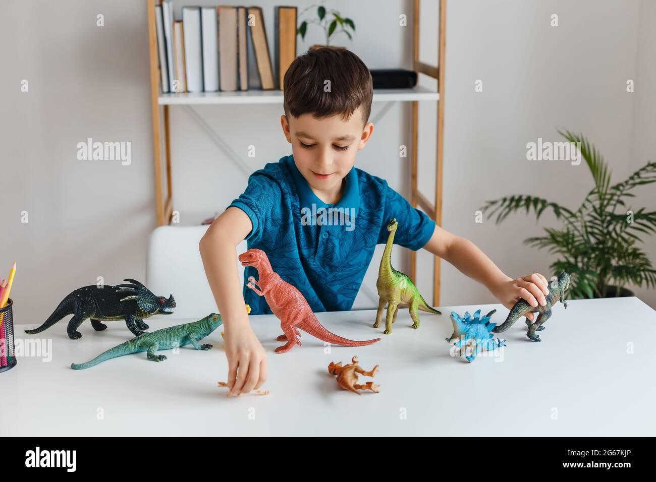 Fokussiertes Kind, das zu Hause mit Dinosauriern spielt. Junge lernt Paläontologie von Dino-Spielzeug in der Freizeit. Konzept von klugen Kindern und frühen Bildung Stockfoto