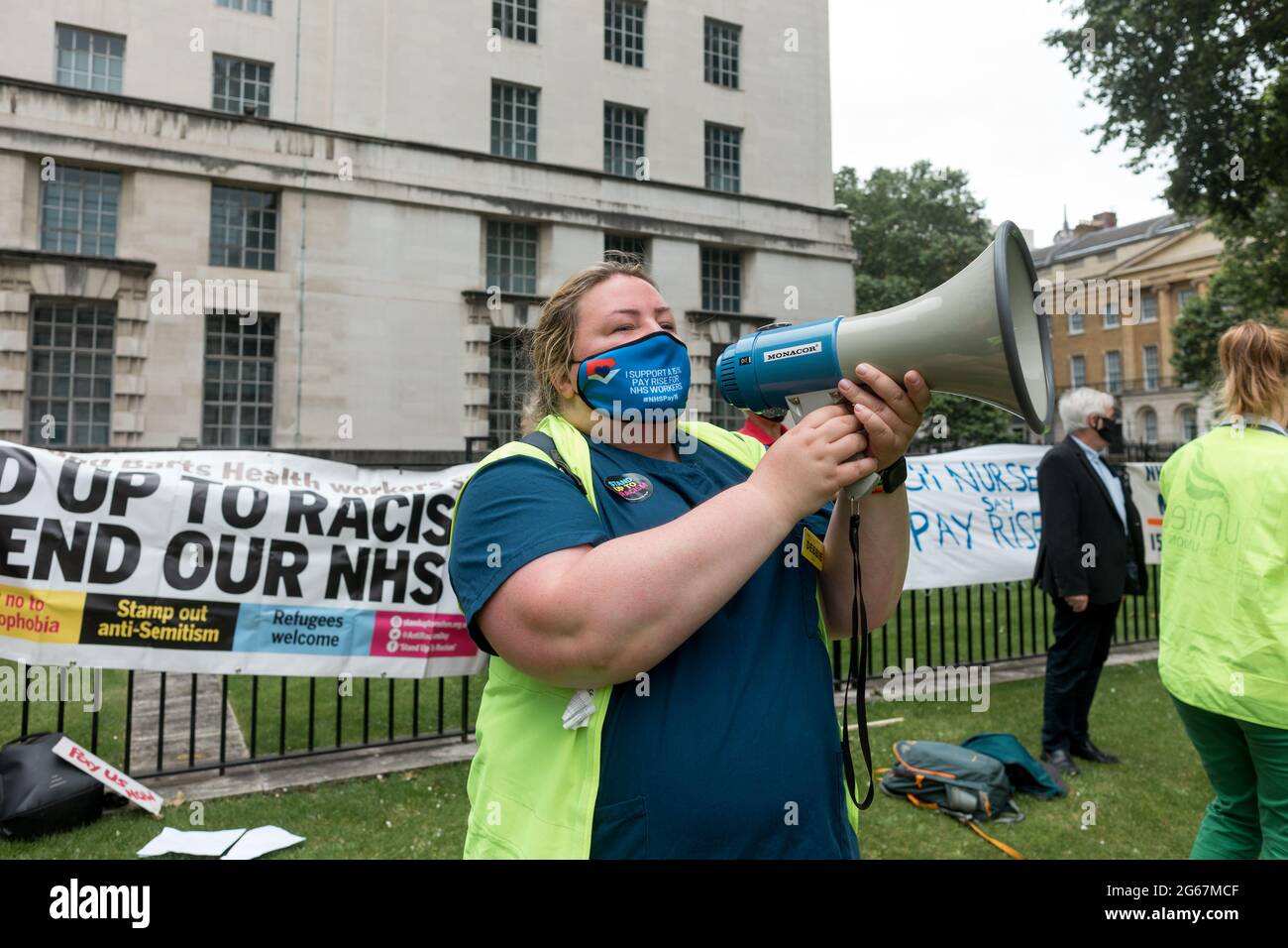 London, Großbritannien. Juli 2021. Ein Protestler, der während des marsches auf einem Megaphon vor der Downing Street spricht.während der Pandemie hat der NHS Unterbesetzung erlebt. Mitarbeiter im Gesundheitswesen arbeiten seit langem und sind in Bezug auf die Versorgung großer Mengen von COVID 19 Fällen unter Stress. Organisiert von Unite the Union, fand eine demonstration statt, die die von der Regierung Boris Johnson vorgeschlagene Gehaltserhöhung um 1 % und die Forderung nach einer Gehaltserhöhung um 15 % vom University College Hospital über den Trafalgar Square forderte und vor der Downing Street endete. Kredit: SOPA Images Limited/Alamy Live Nachrichten Stockfoto