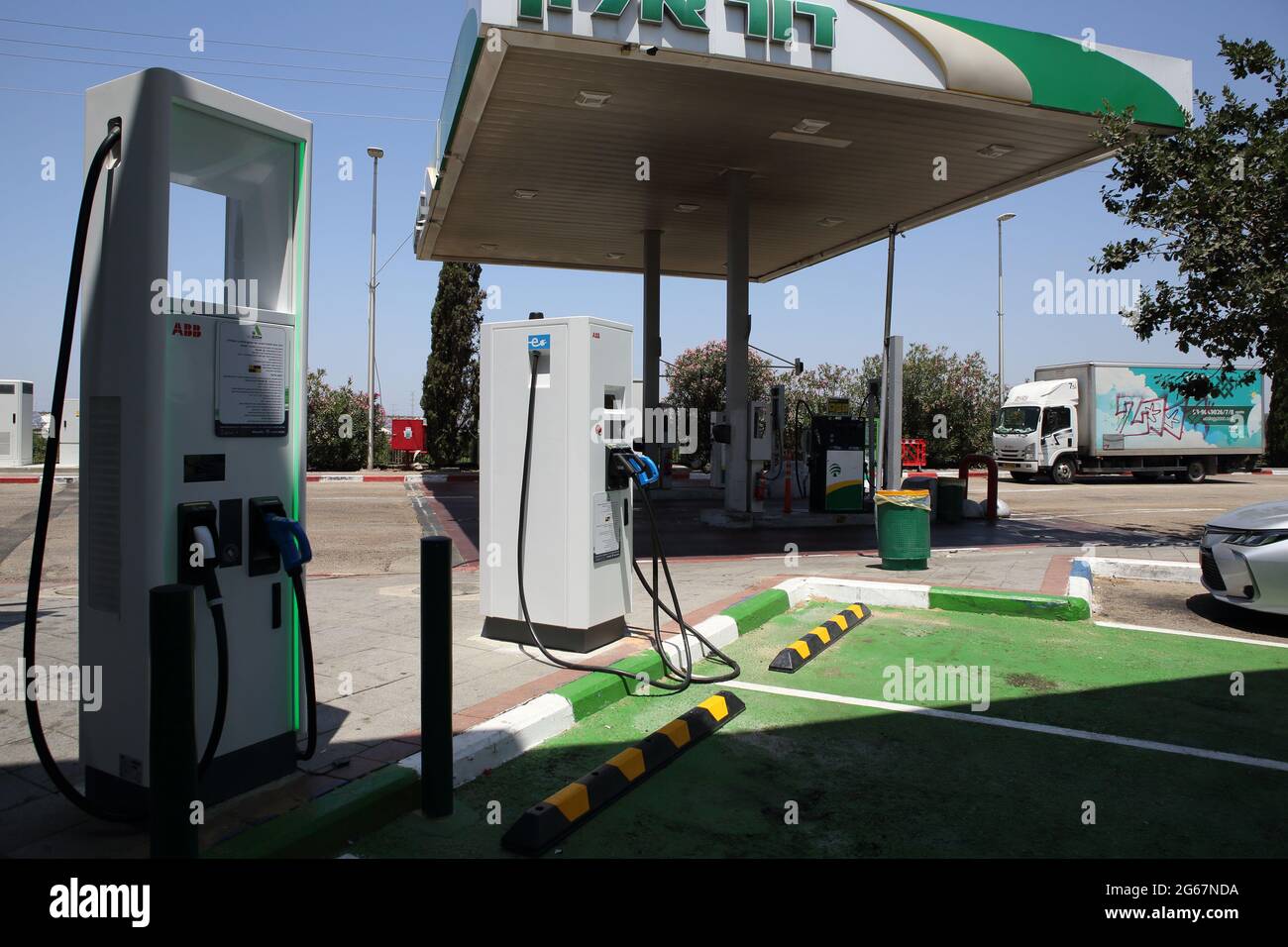 Zwei Ladestationen für Elektroautos mit ausgewiesenen grünen Parkplätzen für Elektroautos nur an einer regulären Gas- oder Tankstelle. Stockfoto