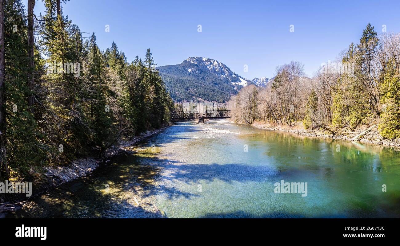 Eine Brücke über den South Fork Skykomish River im Washing State mit Bergen im Hintergrund. Stockfoto