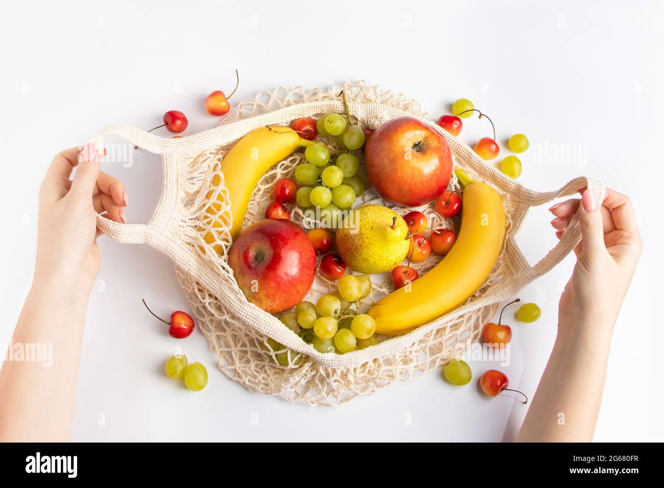 Die Hände von Frauen halten eine umweltfreundliche Netztasche mit Früchten. Vegane Bio-Lebensmittel. Zero Waste und nachhaltiges Lifestyle-Konzept. Stockfoto