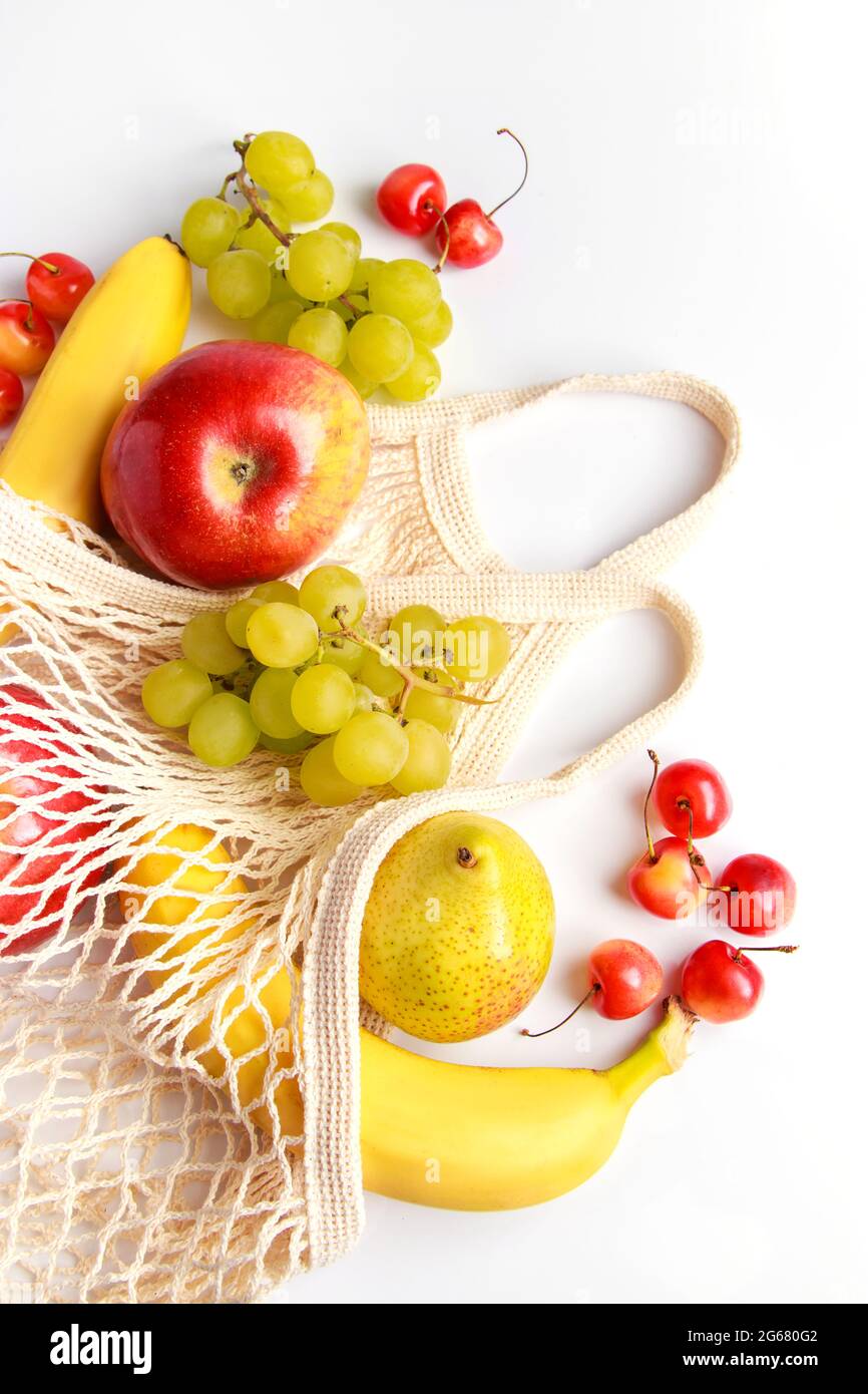 Reife Bio-Früchte in umweltfreundlichem Netzbeutel auf weißem Hintergrund. Trendige Saitentasche zum Einkaufen. Gesundes Essen und nachhaltiges Lifestyle-Konzept. Stockfoto