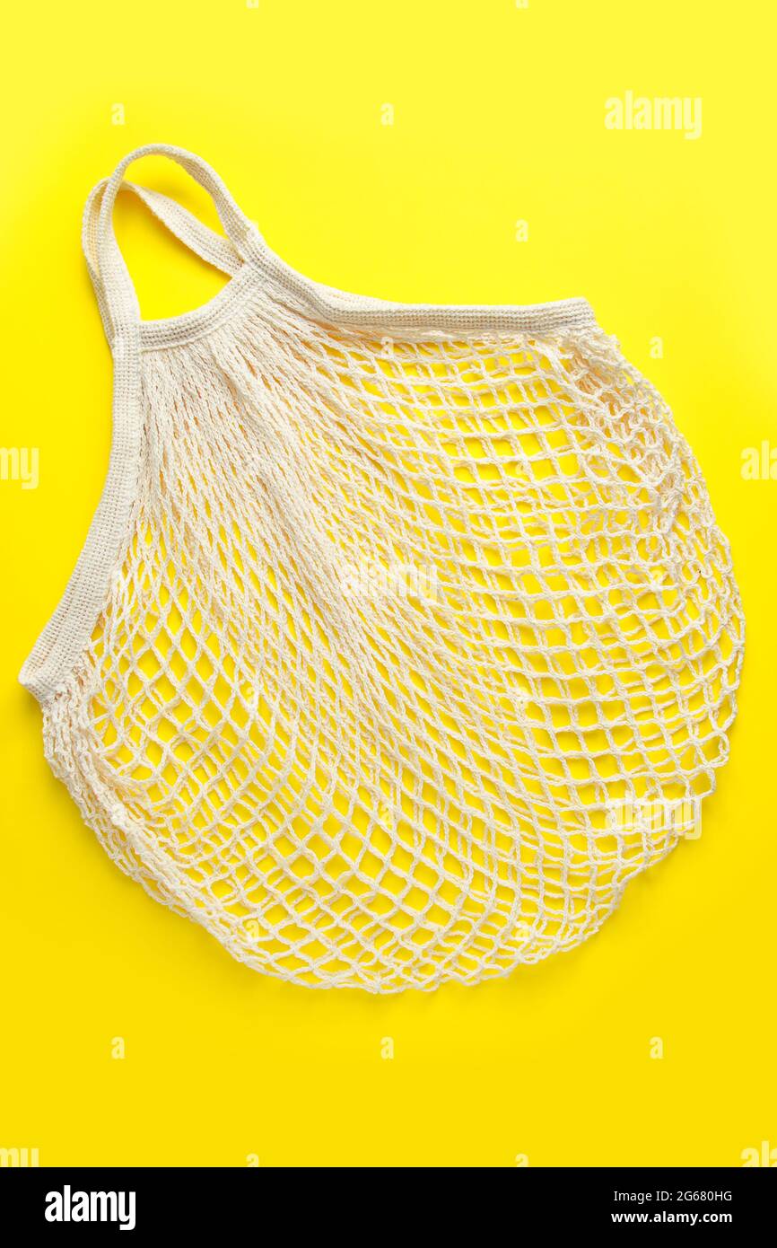 Umweltfreundliche Netztasche auf gelbem Hintergrund. Recycelbare Tasche aus Bio-Baumwolle. Nachhaltiger Lifestyle und Shopping. Stockfoto
