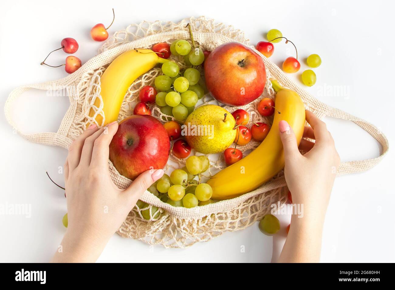 Frau legt reife Früchte in einen umweltfreundlichen Netzbeutel zum Einkaufen. Weibliche Hände halten einen Baumwollstringbeutel mit Bio-Produkten aus der Landwirtschaft. Nachhaltiges Livestyl Stockfoto