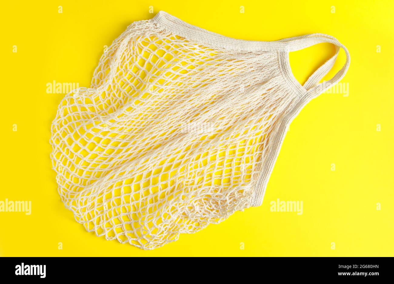 Umweltfreundliche Netztasche auf gelbem Hintergrund. Recycelbare Tasche aus Bio-Baumwolle. Nachhaltiger Lifestyle und Shopping. Stockfoto