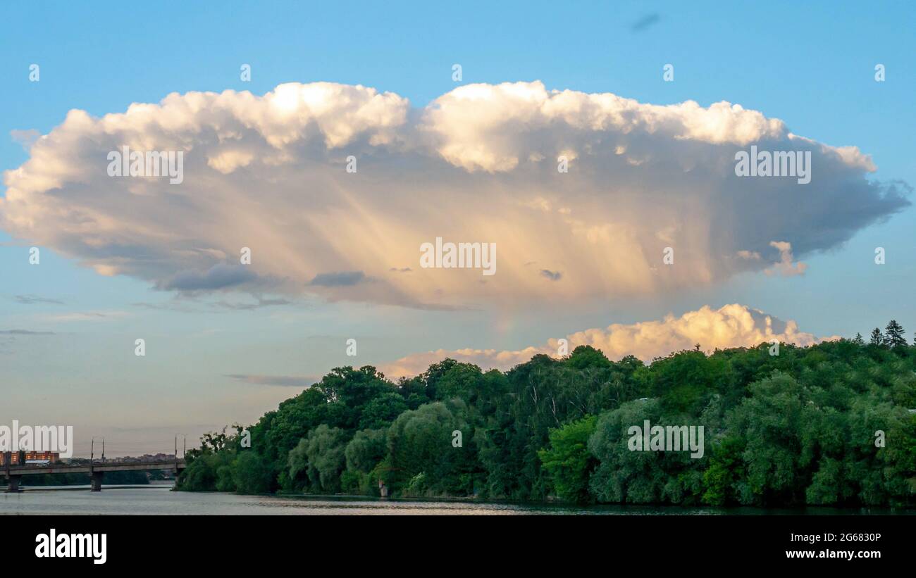 Mystische Wolken, Wolken in Form einer fremden Platte, schöner Himmelshintergrund mit weißen und flauschigen Wolken über dem Wald. Stockfoto