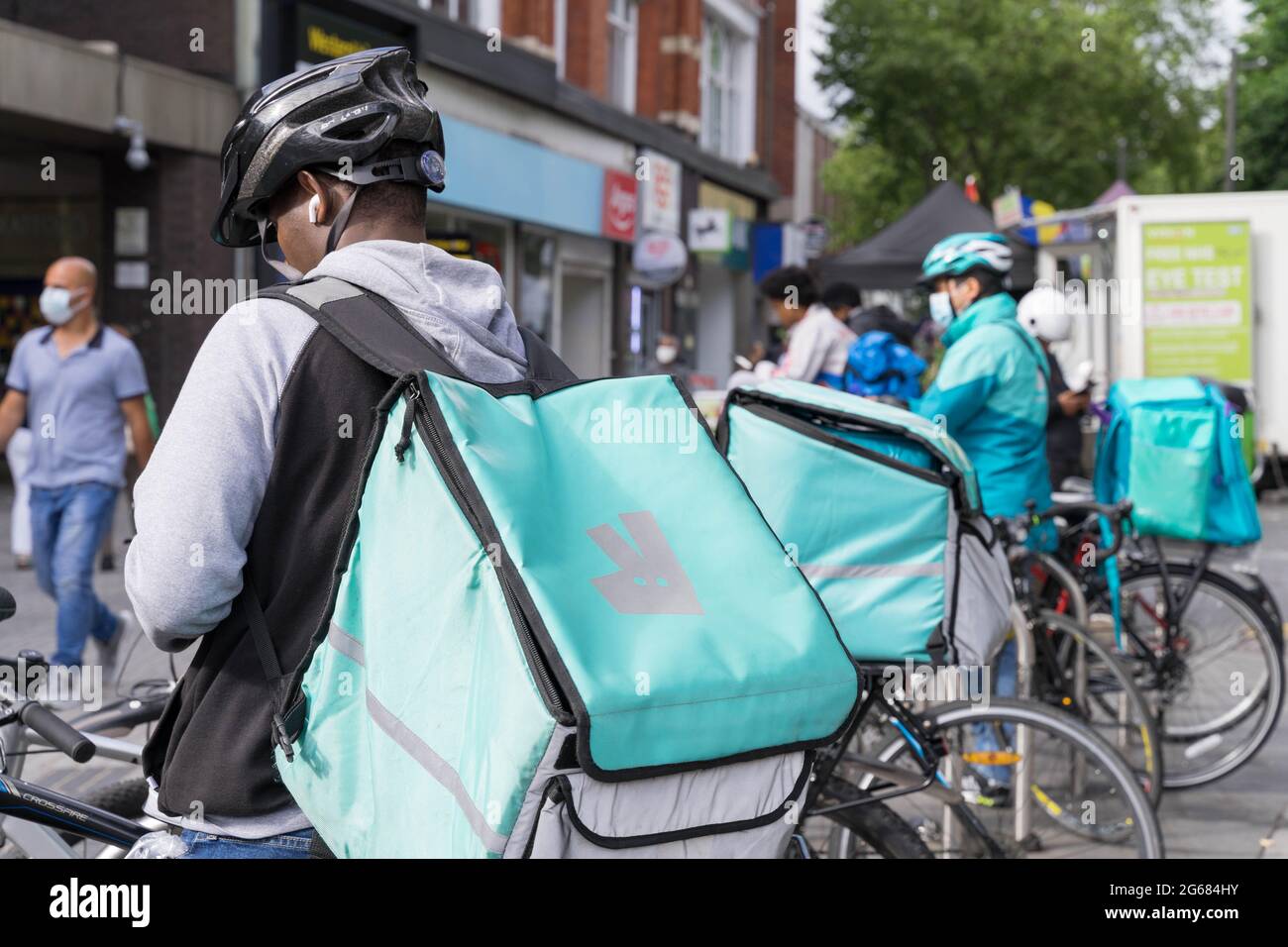 Fast Food Delivery Guys von Deliveroo warten in der Schlange vor dem Restaurant in London Street, England, Großbritannien Stockfoto