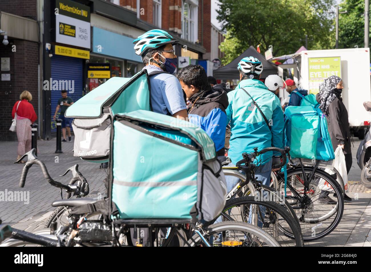 Fast Food Delivery Guys von Deliveroo warten in der Schlange vor dem Restaurant in London Street, England, Großbritannien Stockfoto