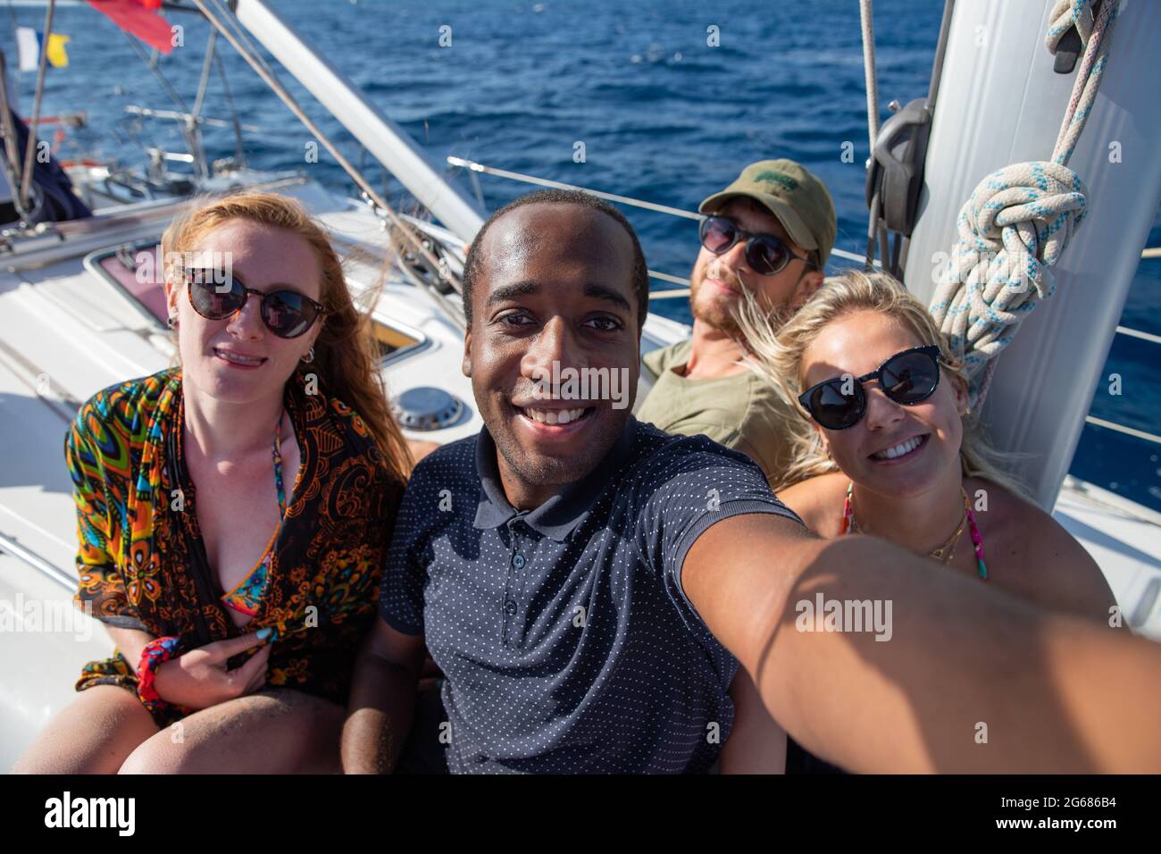 Eine multiethnische Gruppe lächelnder Menschen in einem Boot, die ein Selfie machen. Sommerbild, Freizeit und sorgloses Konzept. Stockfoto