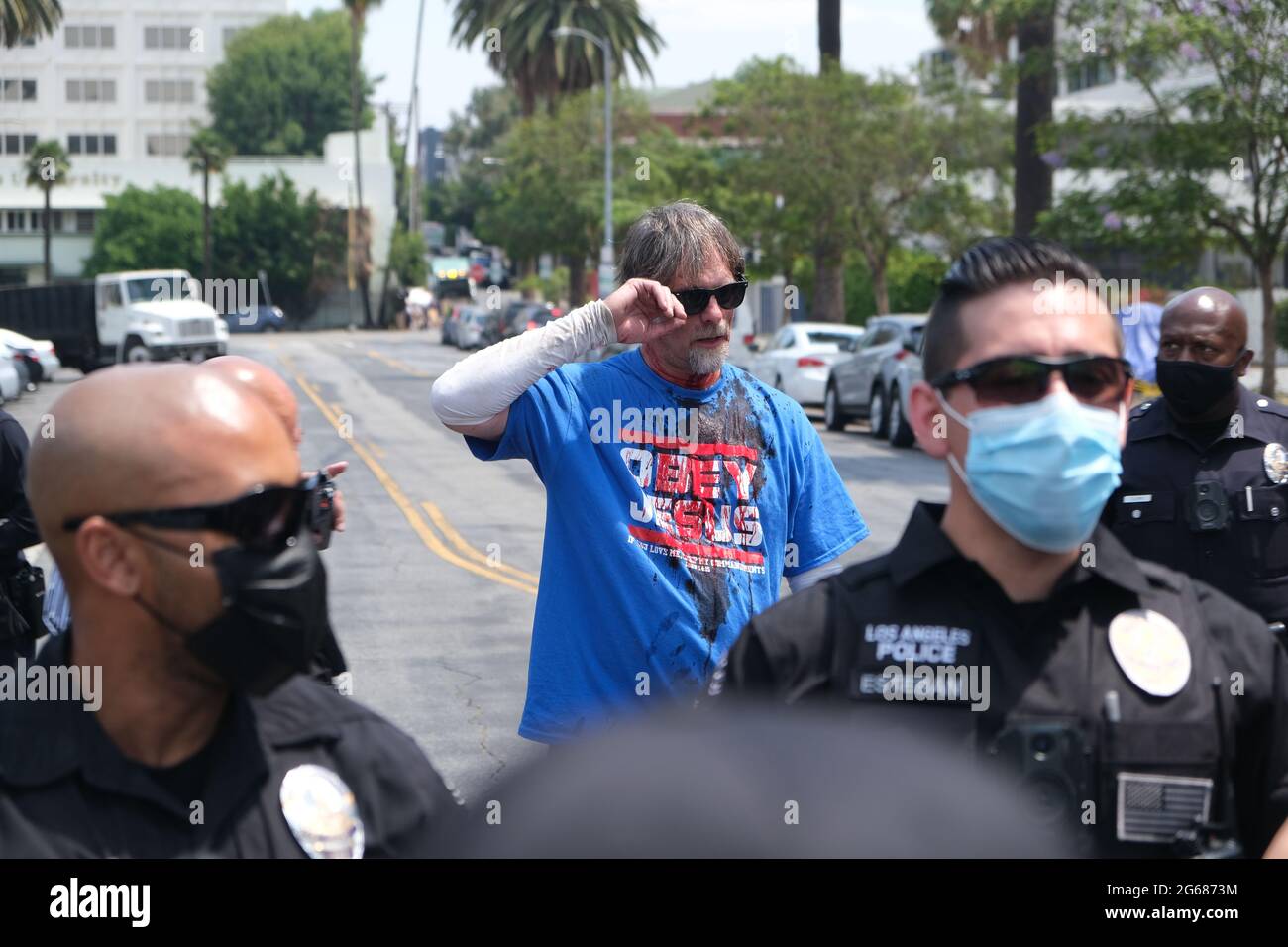 Los Angeles, CA, USA. Juli 2021. Ein Mann, der zuvor angegriffen worden war, steht bei einem Protest gegen ein Koreatown Spa namens Wi Spa am Samstag hinter einer Reihe von Polizeibeamten. Der anfängliche Protest, der gegen die Politik der SPA in Bezug auf Transgender-Kunden geplant war, wurde mit einem pro-Transgender-Protest gegen Transgender getroffen. Quelle: Young G. Kim/Alamy Live News Stockfoto