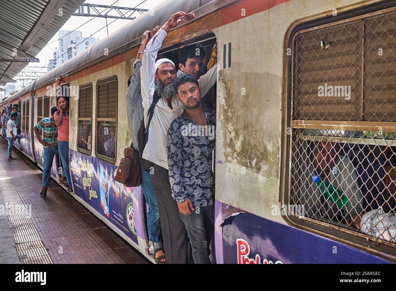 Pendler in einem lokalen Zug am Bahnhof Matunga, Mumbai (Bombay), Indien, verschüttet fast aus den ständig geöffneten Kutschentüren Stockfoto