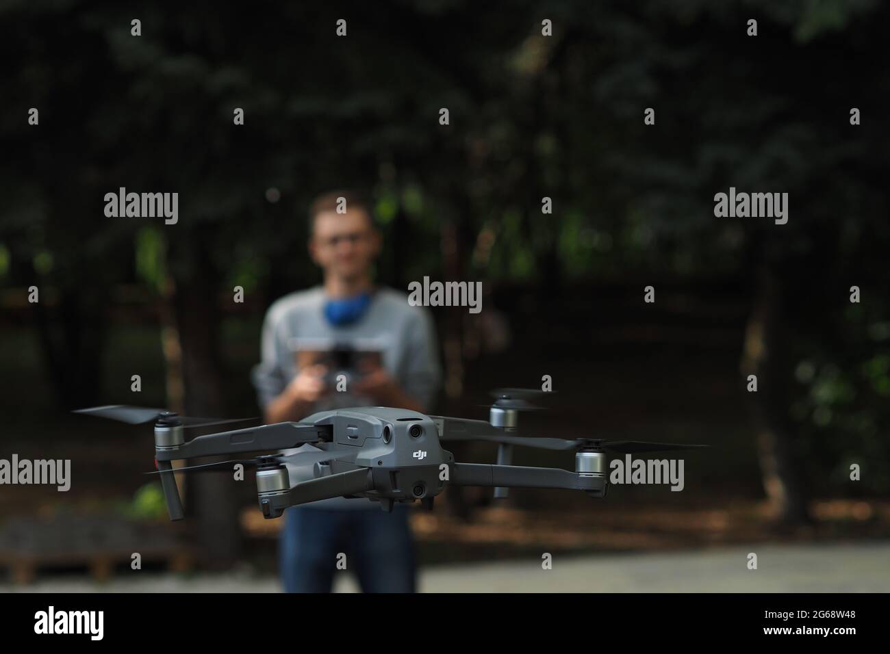 DJI-Drohnenpilot. Der junge Mann hält den Drohnencontroller in den Händen und steuert die Mavic-Drohne. Stockfoto