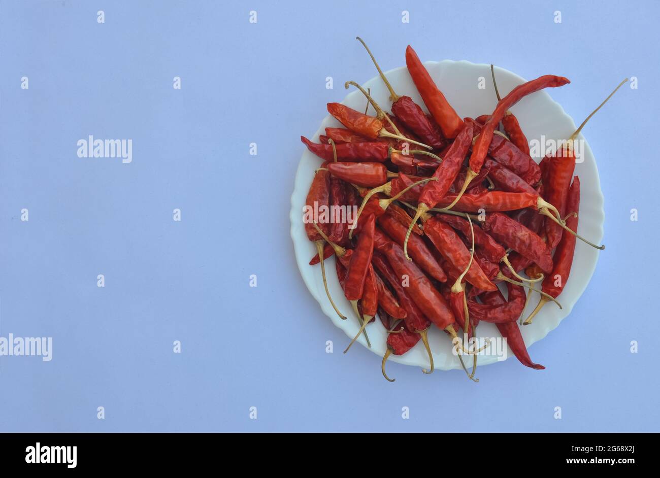 High-Angle-Ansicht von trockenen roten Chilischoten auf der weißen Platte isoliert auf weißem Hintergrund mit Kopierraum Stockfoto