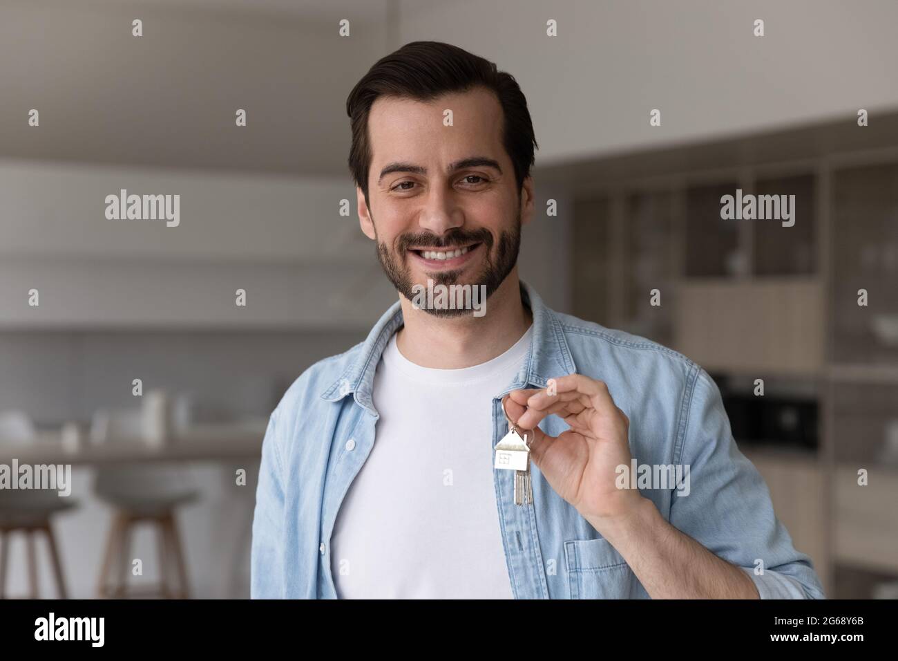 Porträt eines lächelnden Mannes, der die Schlüssel hält und ein Haus kauft Stockfoto