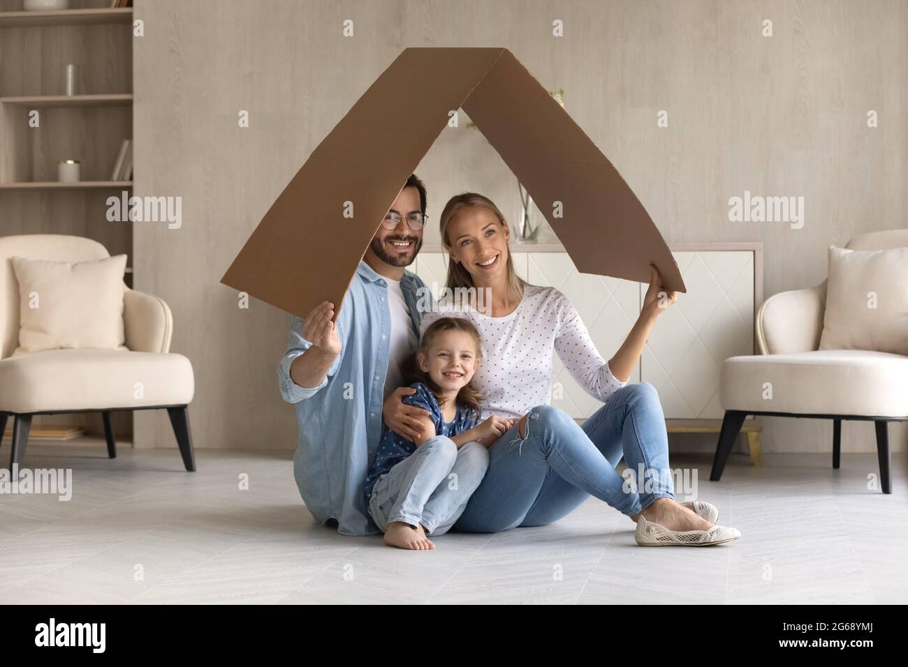 Glückliche Familie mit entzückenden kleinen Tochter, die unter einem Pappdach sitzt Stockfoto