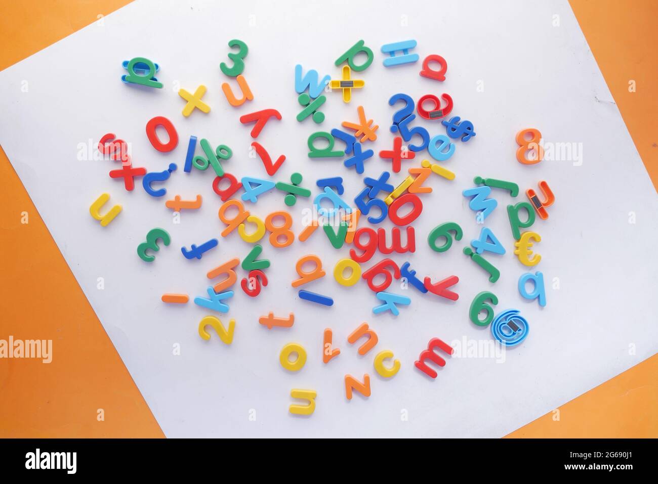 Bunte Plastikbuchstaben auf orangefarbenem Hintergrund, Draufsicht Stockfoto