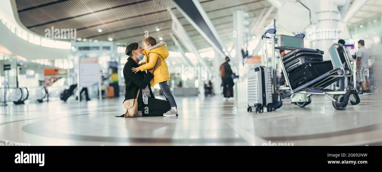 Weitwinkelansicht einer Frau, die ihren Sohn am Flughafenterminal küsst. Mutter trifft ihren Sohn nach langer Trennung während des Covid-19-Ausbruchs. Stockfoto