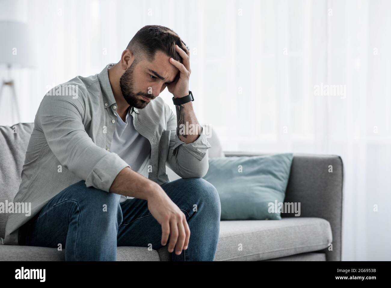 Attraktiver Kerl, der sich verzweifelt, traurig fühlt, besorgt und deprimiert nachdenklich und einsam aussieht Stockfoto