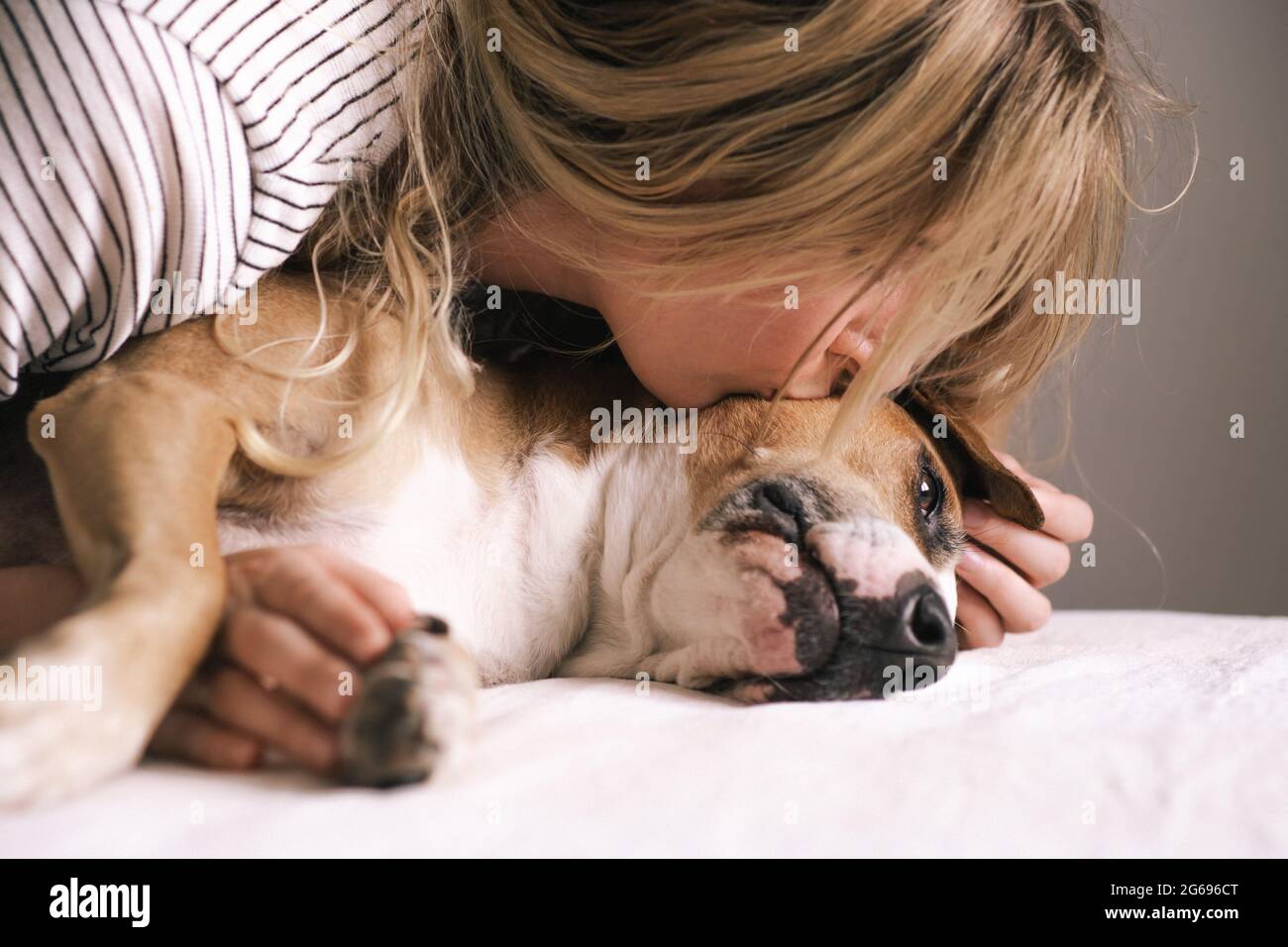 Die junge Frau liegt ihrem Hund nahe und küsst sie. Emotionaler Gesellschaftstyling mit Haustieren Stockfoto