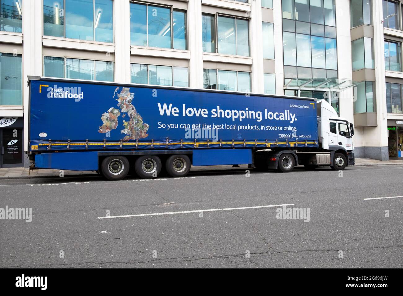 Tesco Lieferwagen Seitenansicht mit Werbung „Wir lieben es, vor Ort einzukaufen“, die vor dem Supermarkt Tescos Smithfield in der City of London, England, geparkt ist Stockfoto